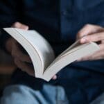 Man in blue shirt reading a book, book picks for integrators