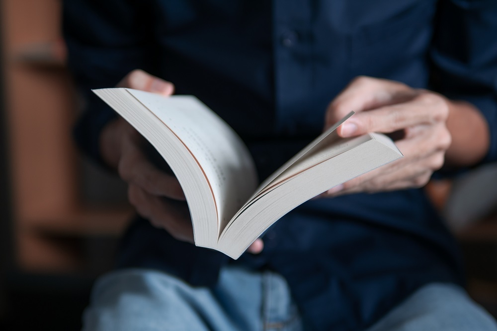 Man in blue shirt reading a book, book picks for integrators