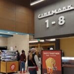 Person looking at digital menu board in movie theater lobby.
