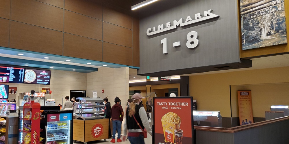 Person looking at digital menu board in movie theater lobby.