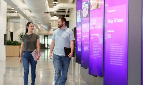 two people walking down hallway lined with LG displays