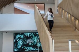 woman walking down stair with videowall in background