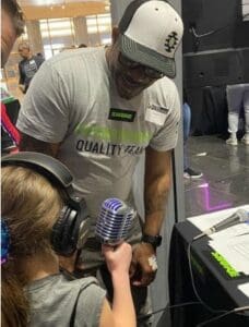 Shure rep helping child with a microphone as part of the STEM program.