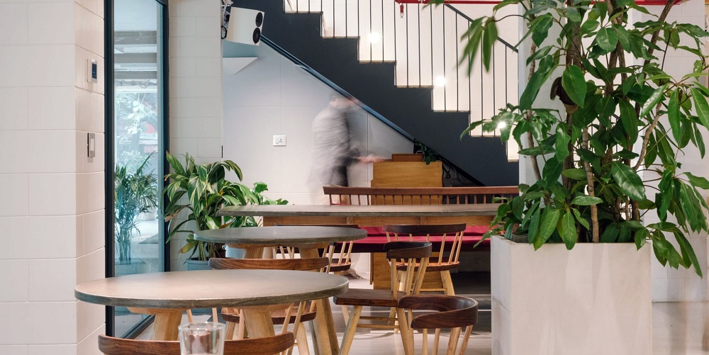 Interior of Fig at Malcha, Delhi. A blurred person is walking around the restaurant tables.