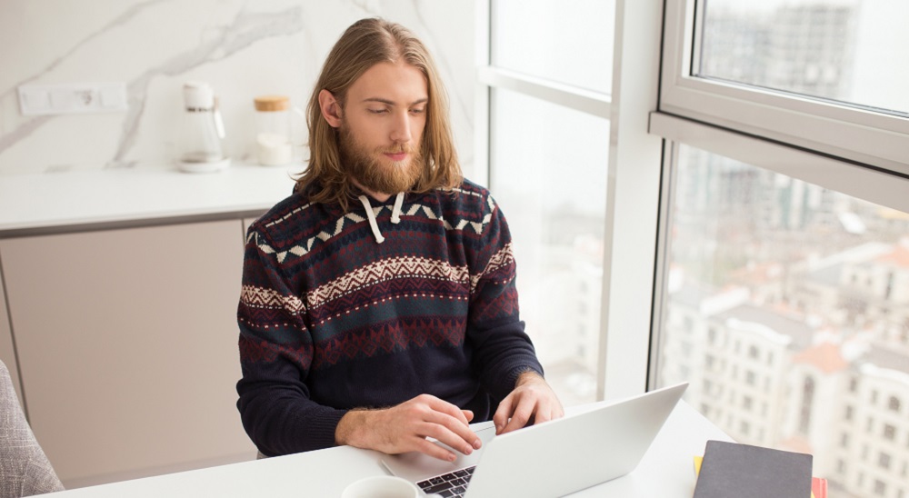 Person sitting in a sweater and working to depict complacency.