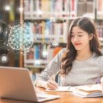 Polygonal brain shape of an artificial intelligence with various icon of smart city Internet of Things Technology over Asian young Student using technology laptop in library of university, higher education