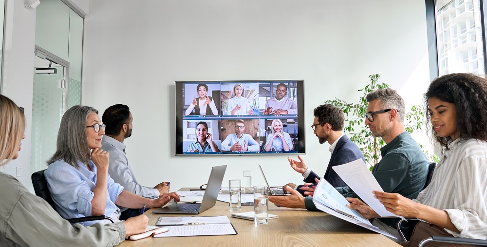 People in a conference room with a video bar and AV system.