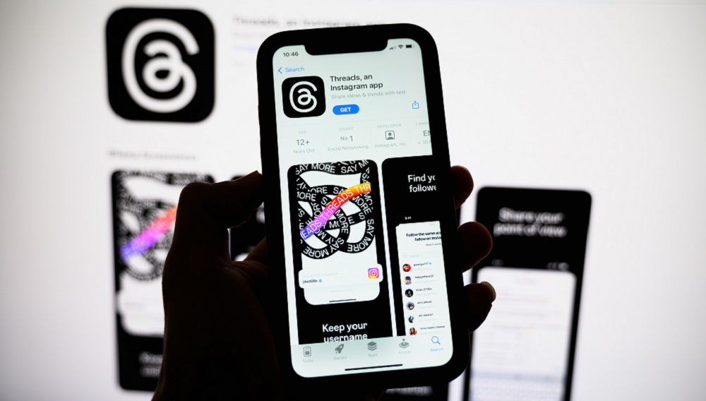Person holding phone with Threads app.
