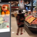 Person in a grocery store walking past a digital signage.