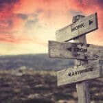 work from anywhere quote caption text written engraved on wooden signpost outdoors in nature with dramatic red skies.