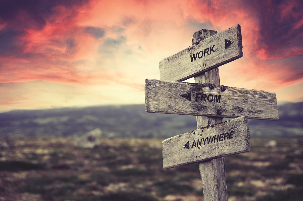 work from anywhere quote caption text written engraved on wooden signpost outdoors in nature with dramatic red skies.