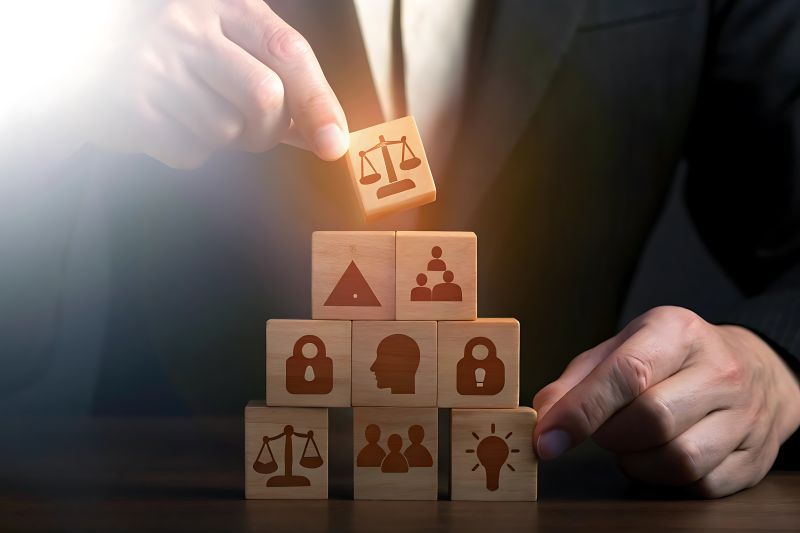 Businessperson Building a Pyramid of Wooden Blocks Representing Legal Compliance Teamwork and Innovation