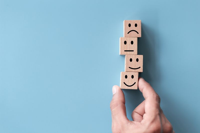 Close up top view customer hand choose smiley face on wood cube, Service rating, satisfaction concept.