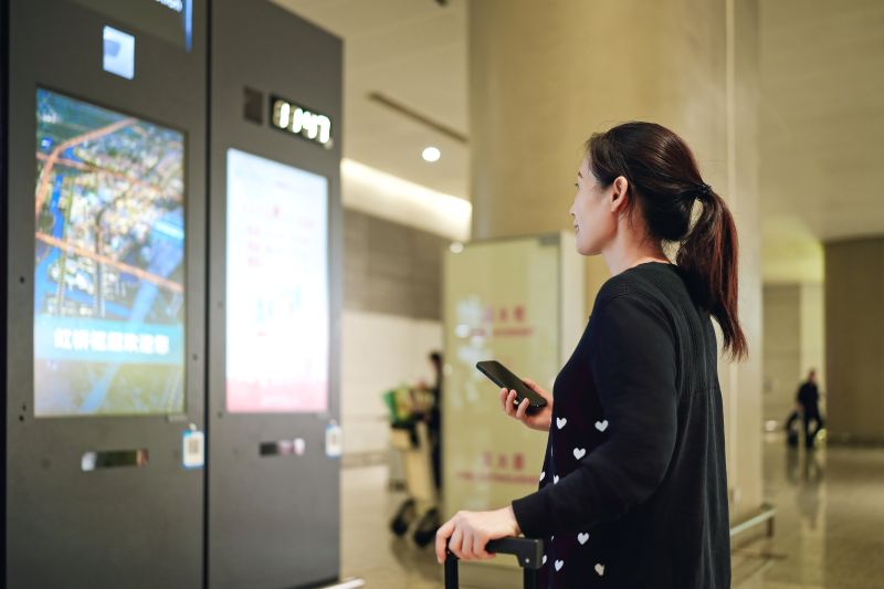 Traveler Interacting with Digital Display at Airport Terminal