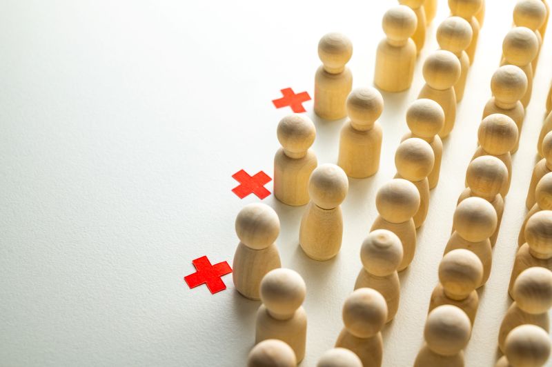 Conceptual representation, with wooden pawns, of corporate layoffs. Concept of layoffs, staff cuts, and mass layoffs.