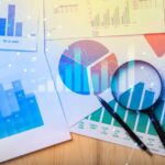 Magnifying glass and documents with analytics data lying on table,selective focus